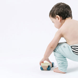 toddler in light blue pants playing with car toy